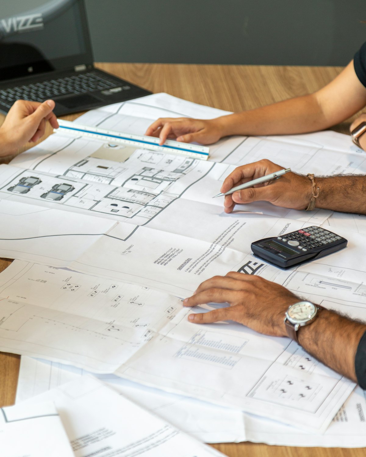 Two people working over a set of house plans with a pencil