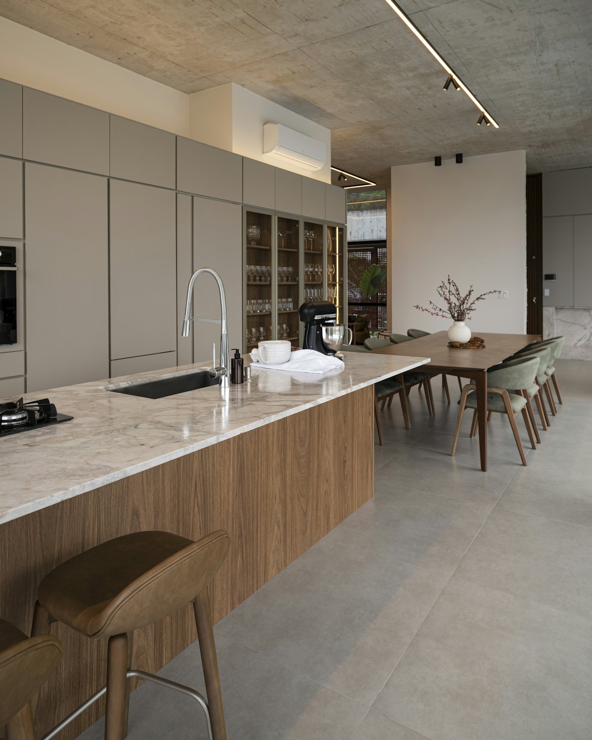 A long walnut kitchen island under a linear ceiling light