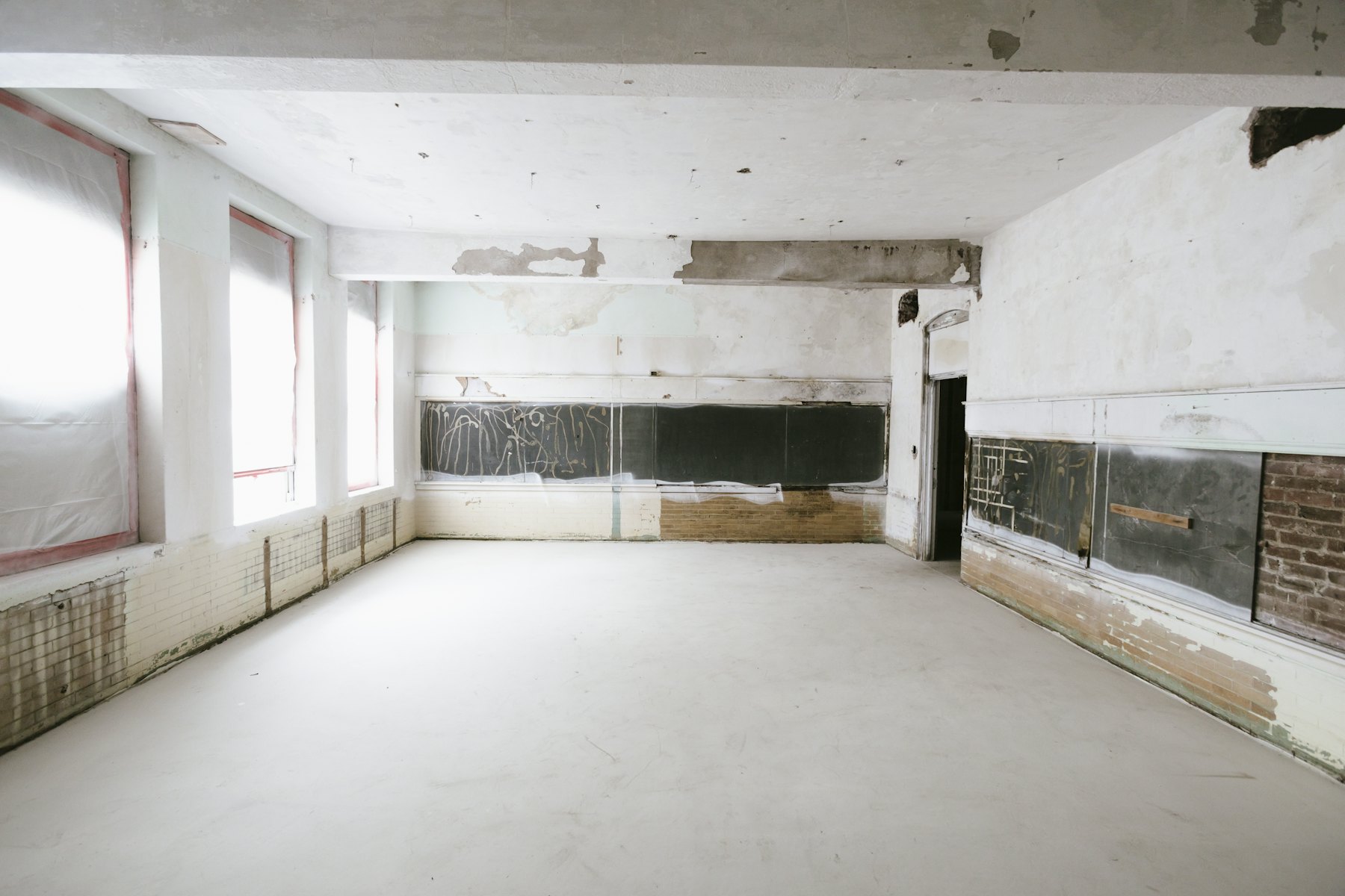 An empty, stripped room with bare concrete floors and peeling walls