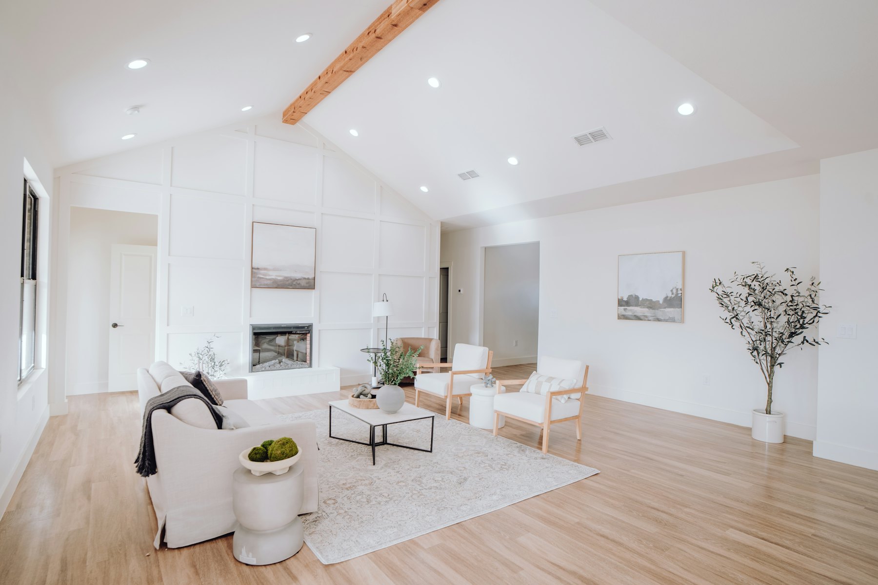 A white living room under a vaulted ceiling with a timber ridge beam