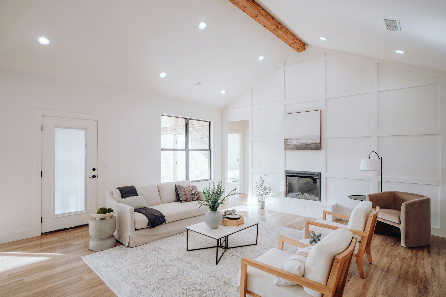 The vaulted living room from the other end, with a white sofa and a floor lamp