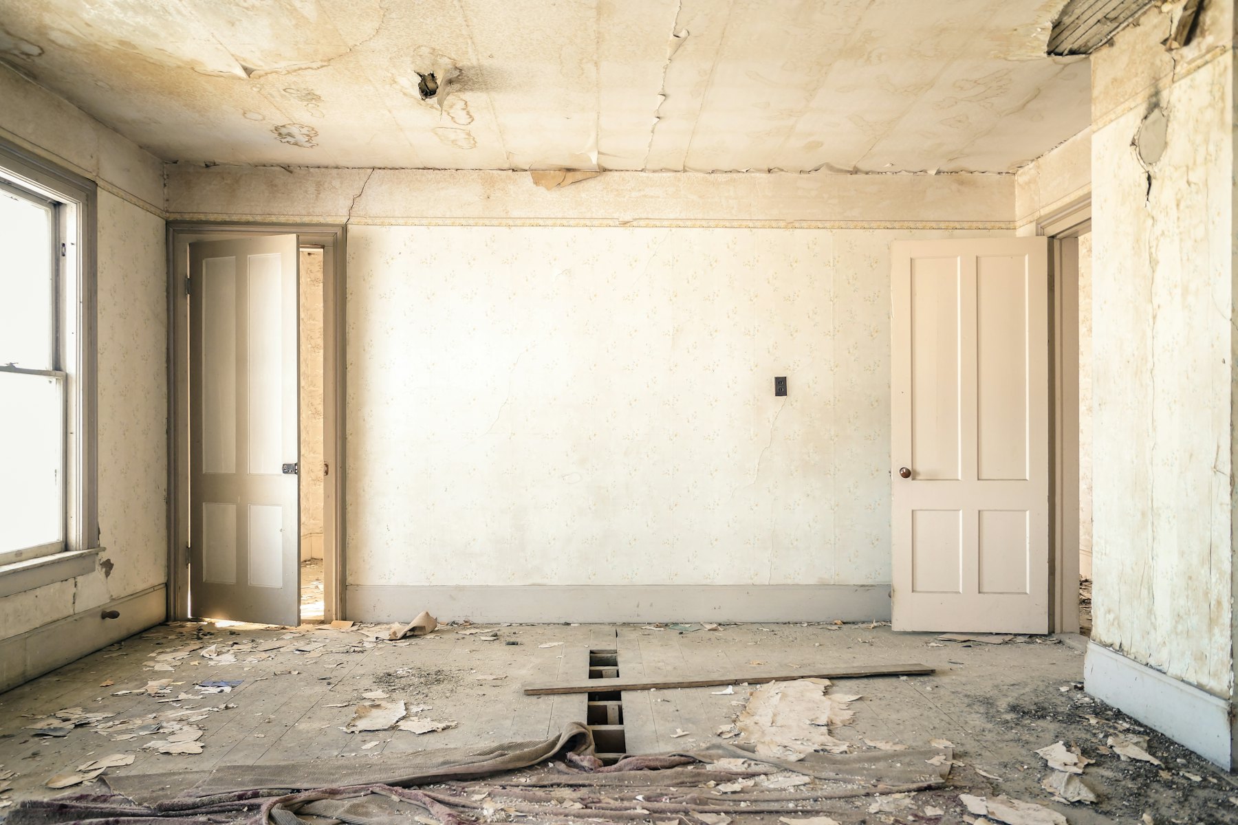 A derelict room with broken plaster, exposed beams and rubble on the floor