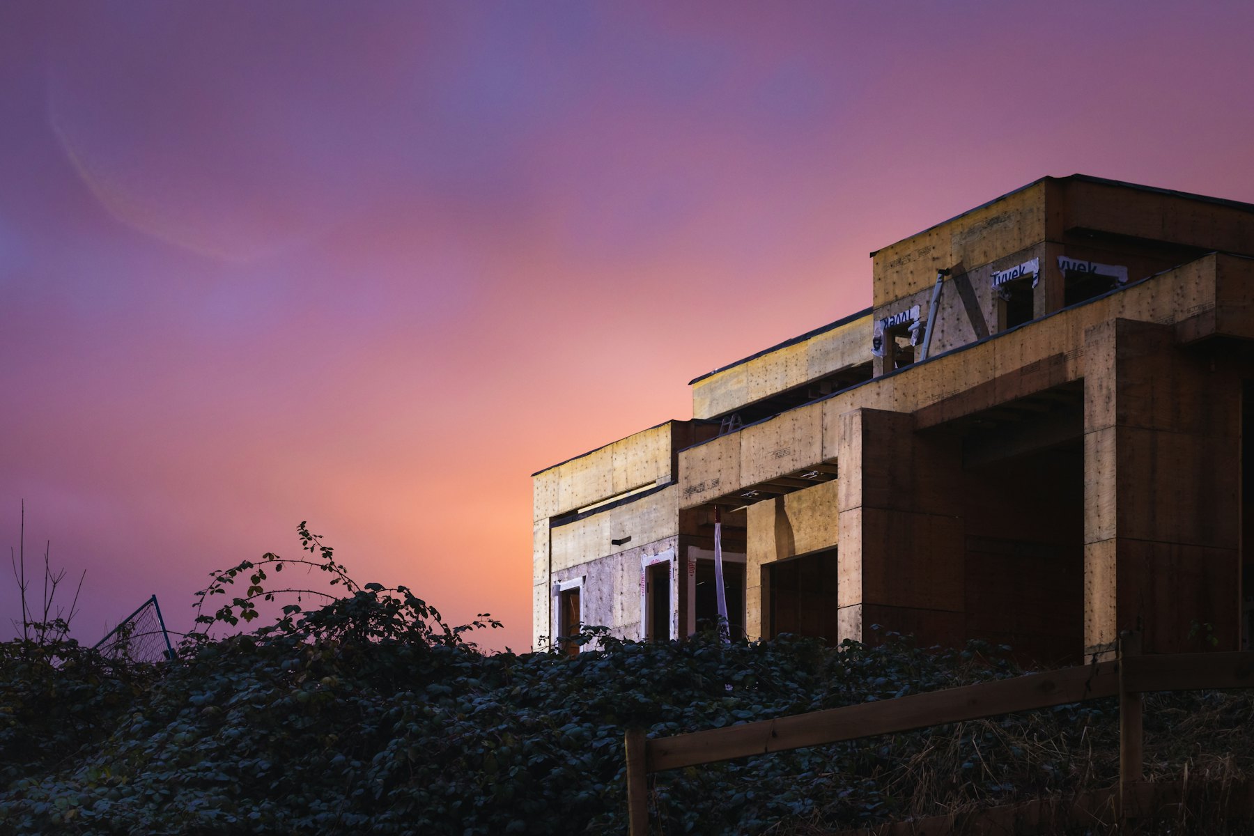 The house at dusk under a purple sky, its rooms lit from inside