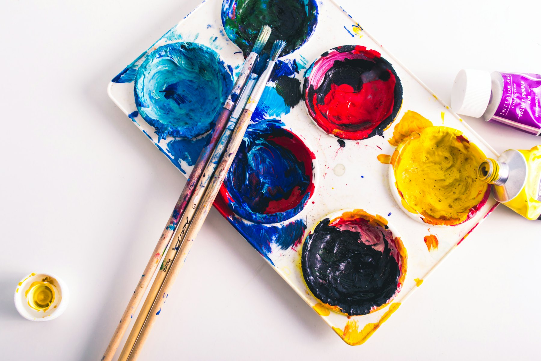 Brushes resting on a palette crowded with mixed paint