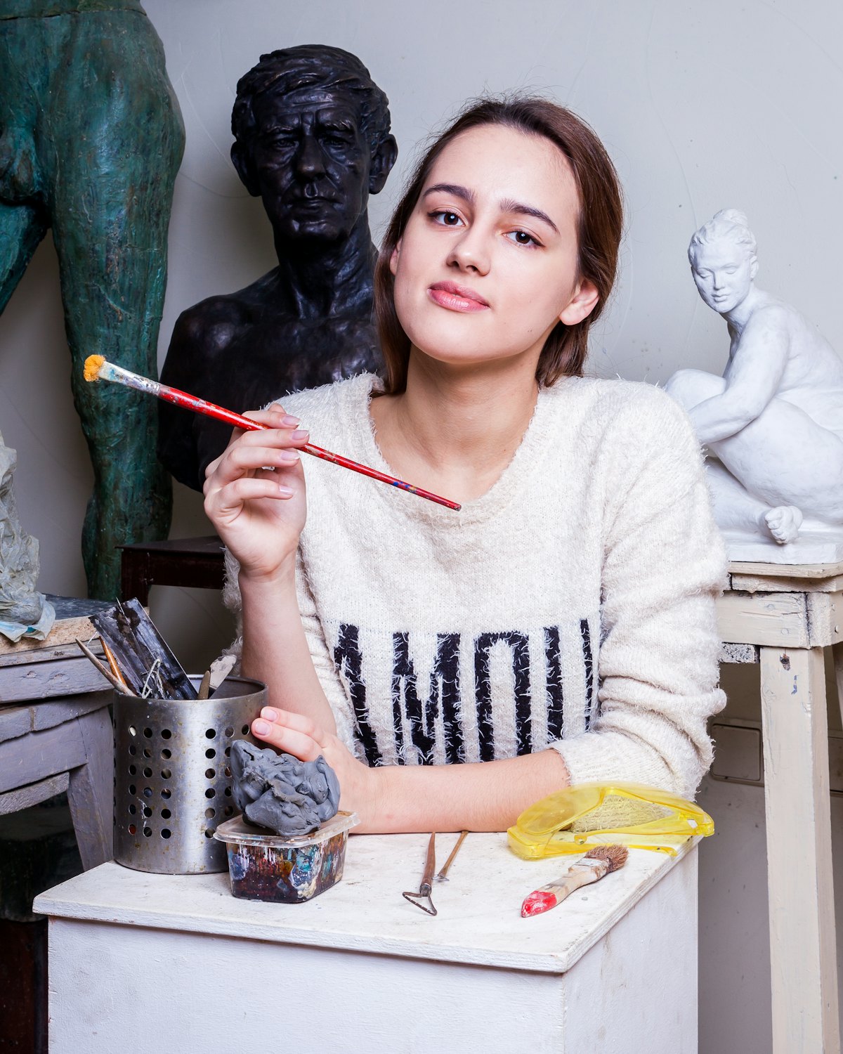 June Marlowe leaning on a work table, holding a paintbrush