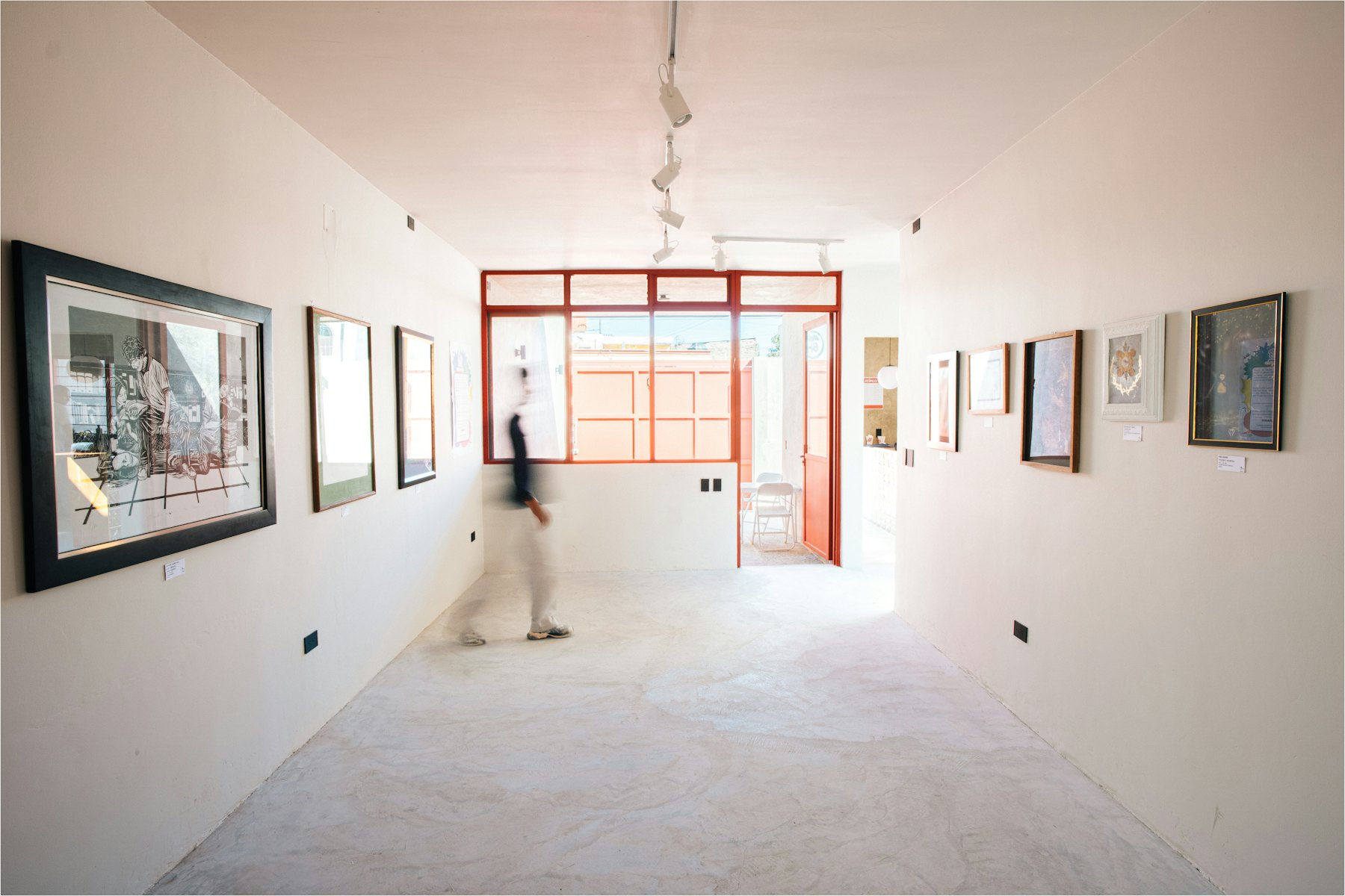 A visitor walking through a bright, minimal gallery