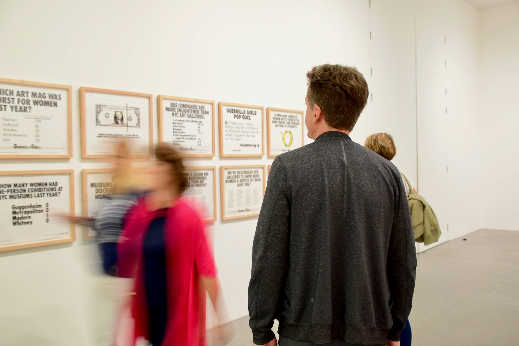 A visitor standing in front of a painting on a gallery wall