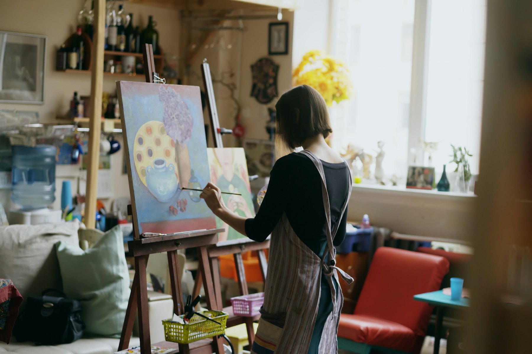 A painter working on a large canvas in a sunlit studio