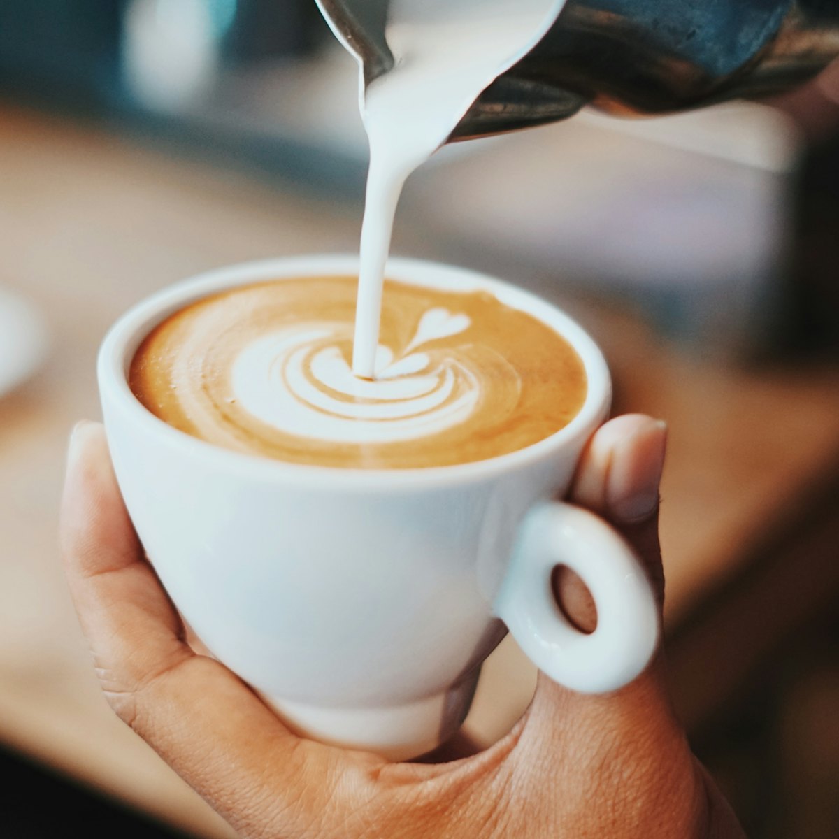 A barista pouring a heart into a latte
