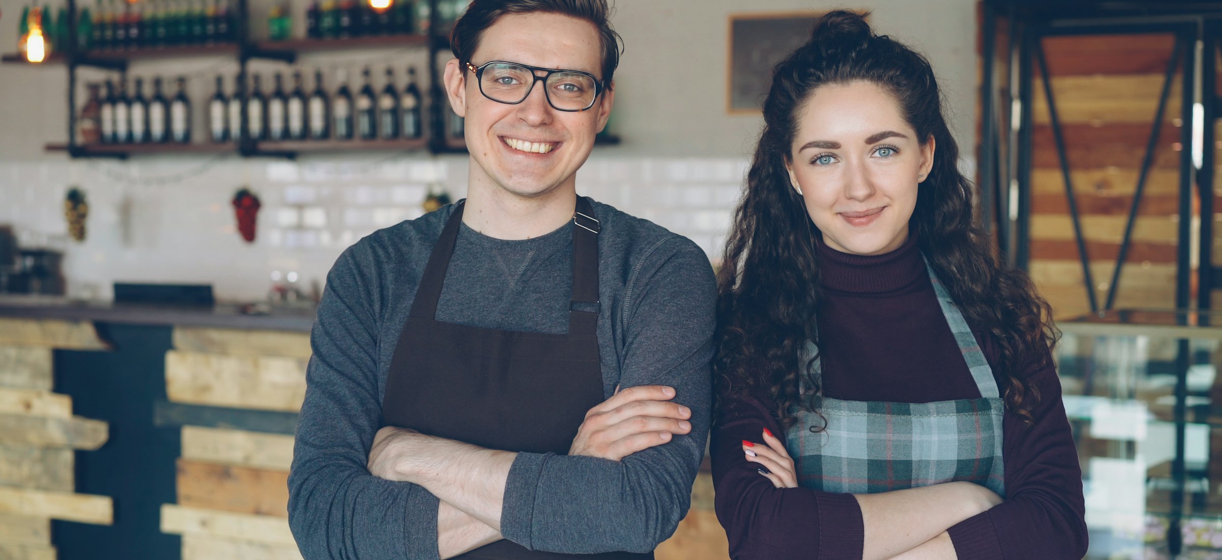 A barista smiling behind the counter of a small coffee shop
