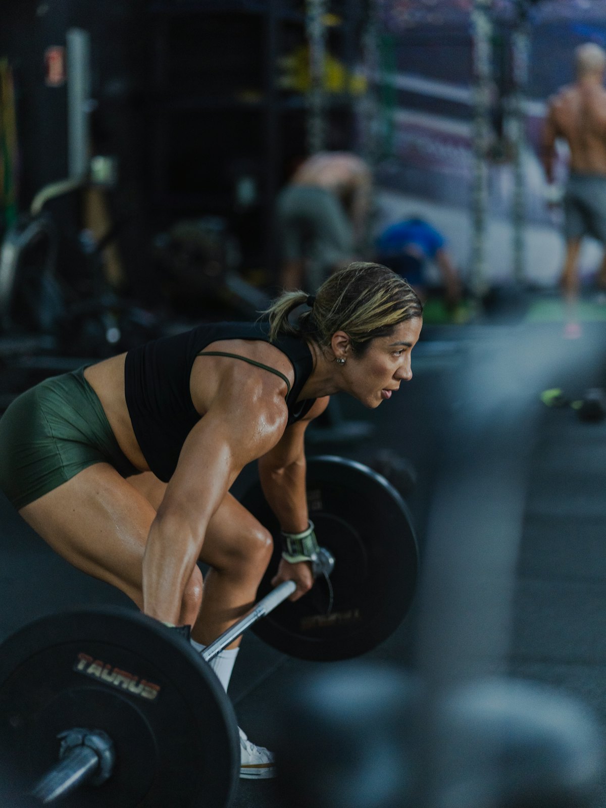A member pulling a heavy deadlift under the gym lights