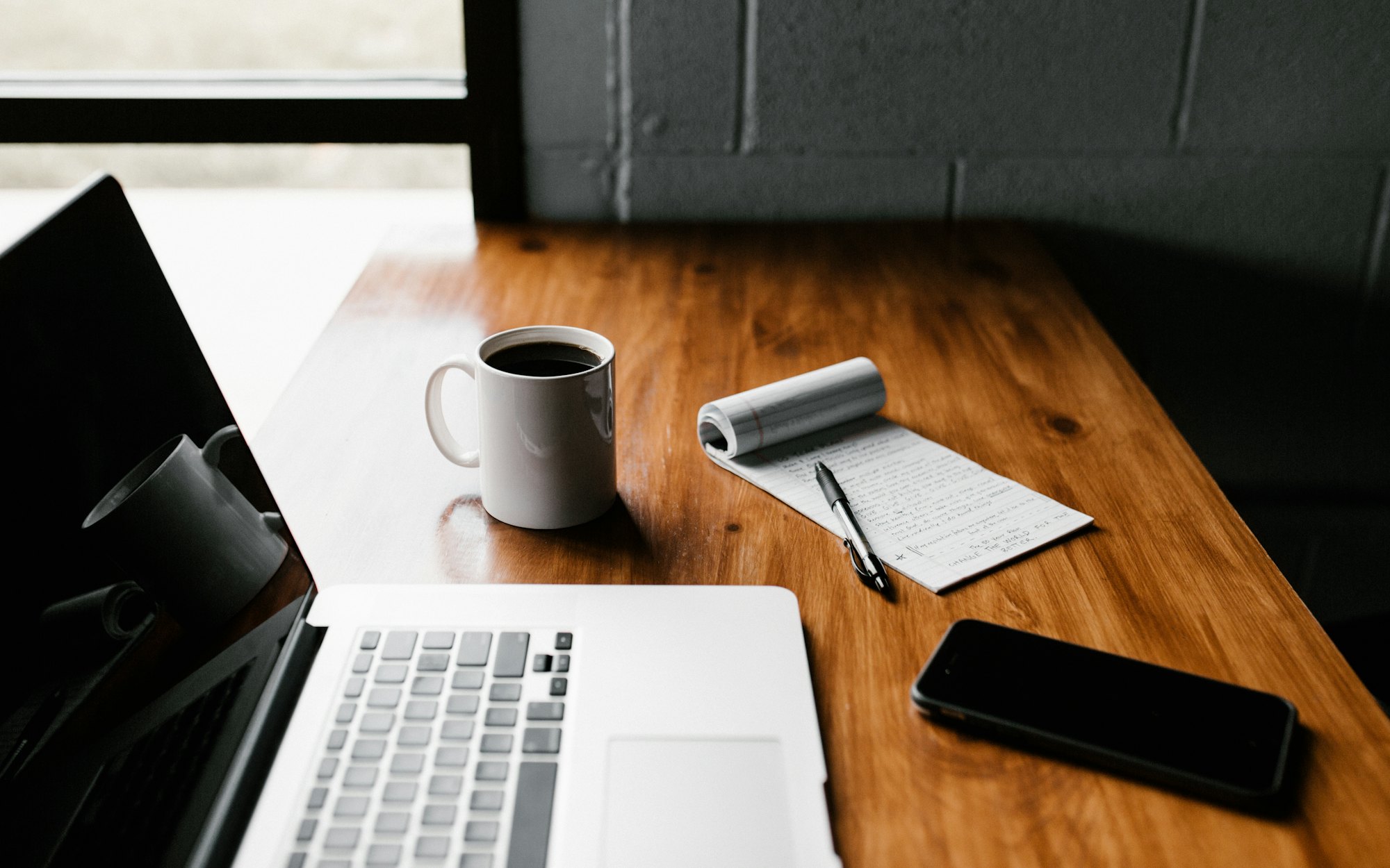 A cup of coffee next to a laptop showing the newsletter