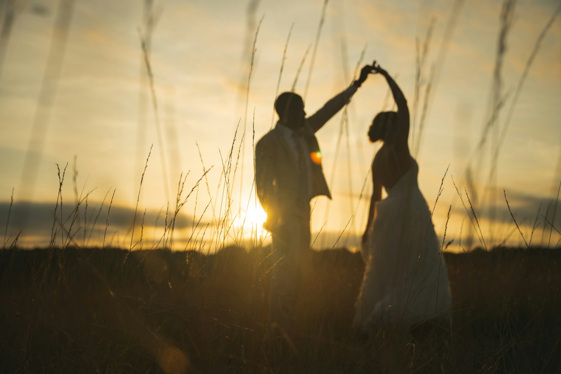 Theo spinning Maya in the grass at sunset