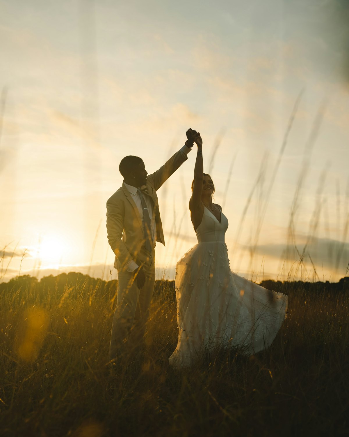 Maya and Theo dancing in the long grass as the sun sets behind them