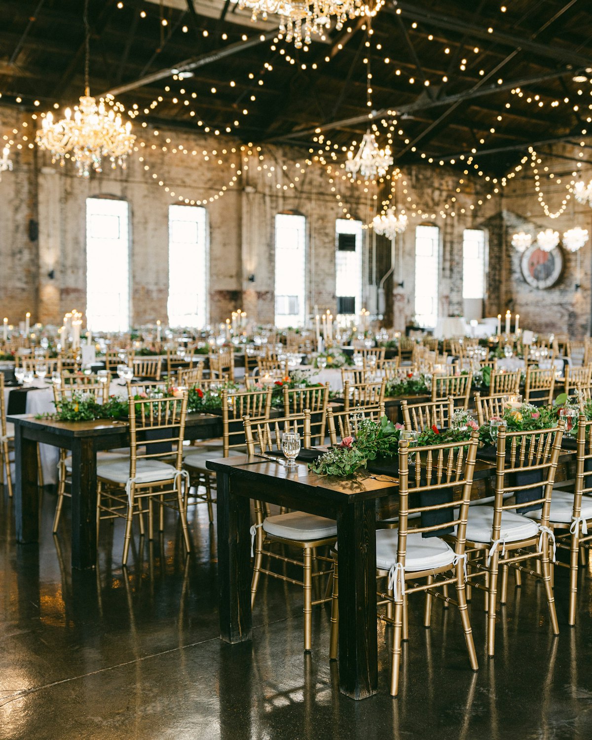 Long reception tables under chandeliers and string lights