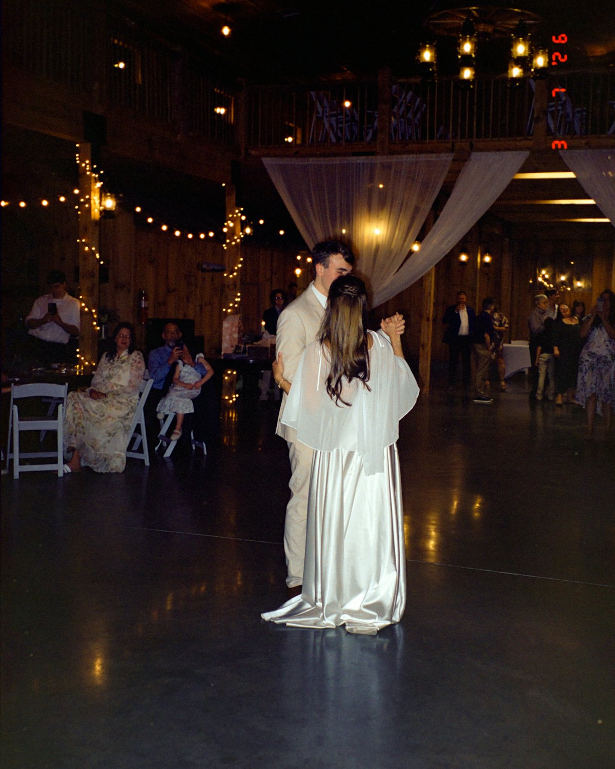 Priya and Sam sharing their first dance under string lights
