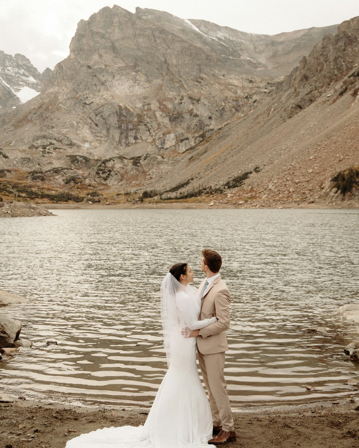 Ava and Jonah holding each other at the edge of a mountain lake