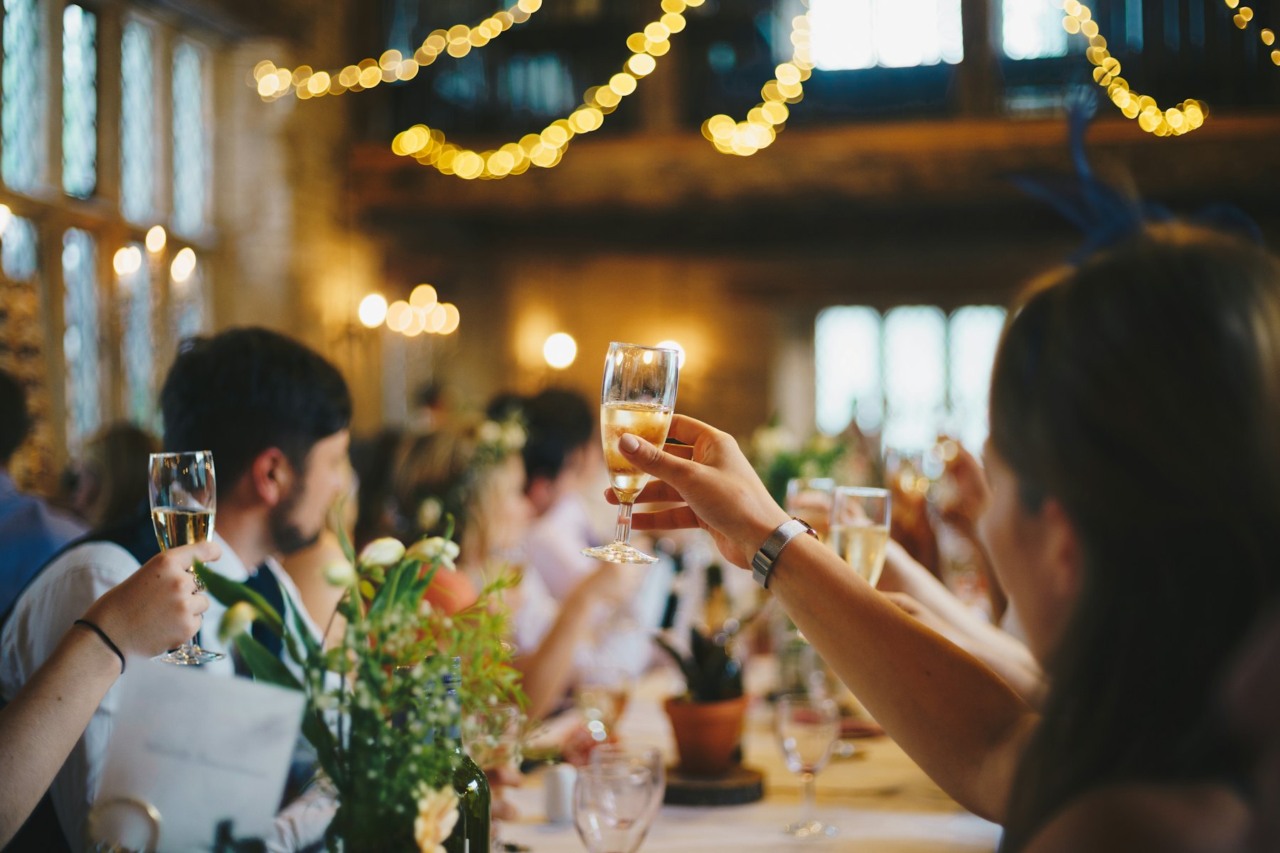 Guests raising their glasses under string lights