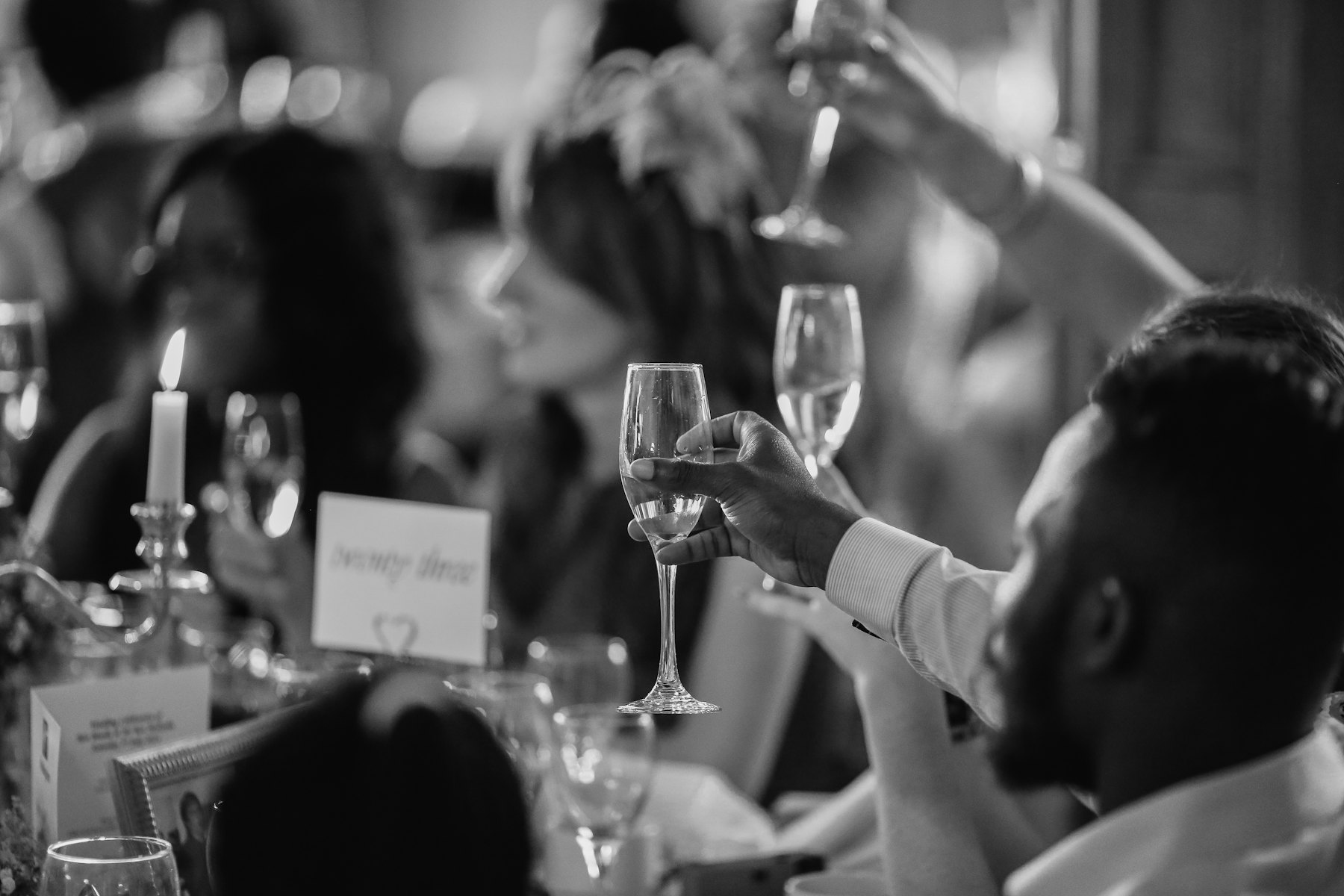 A black and white frame of guests laughing at dinner
