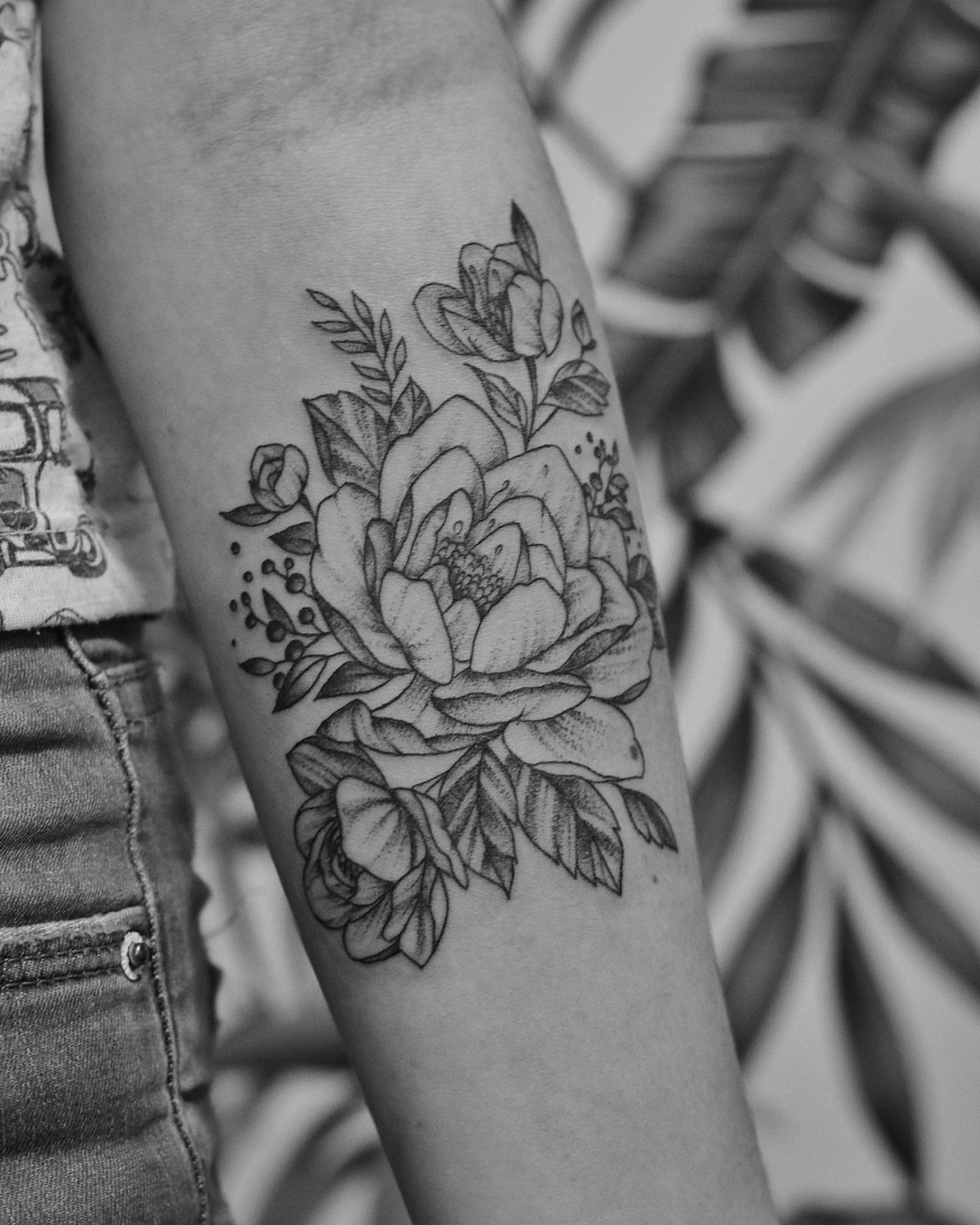 A black and grey peony on a forearm