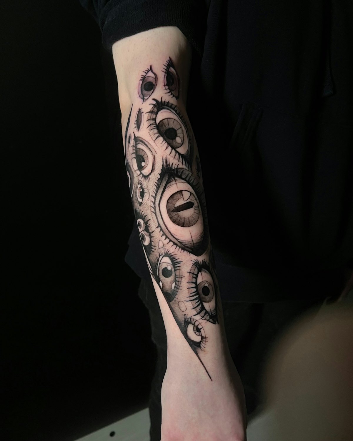 A blackwork forearm piece of repeating eyes