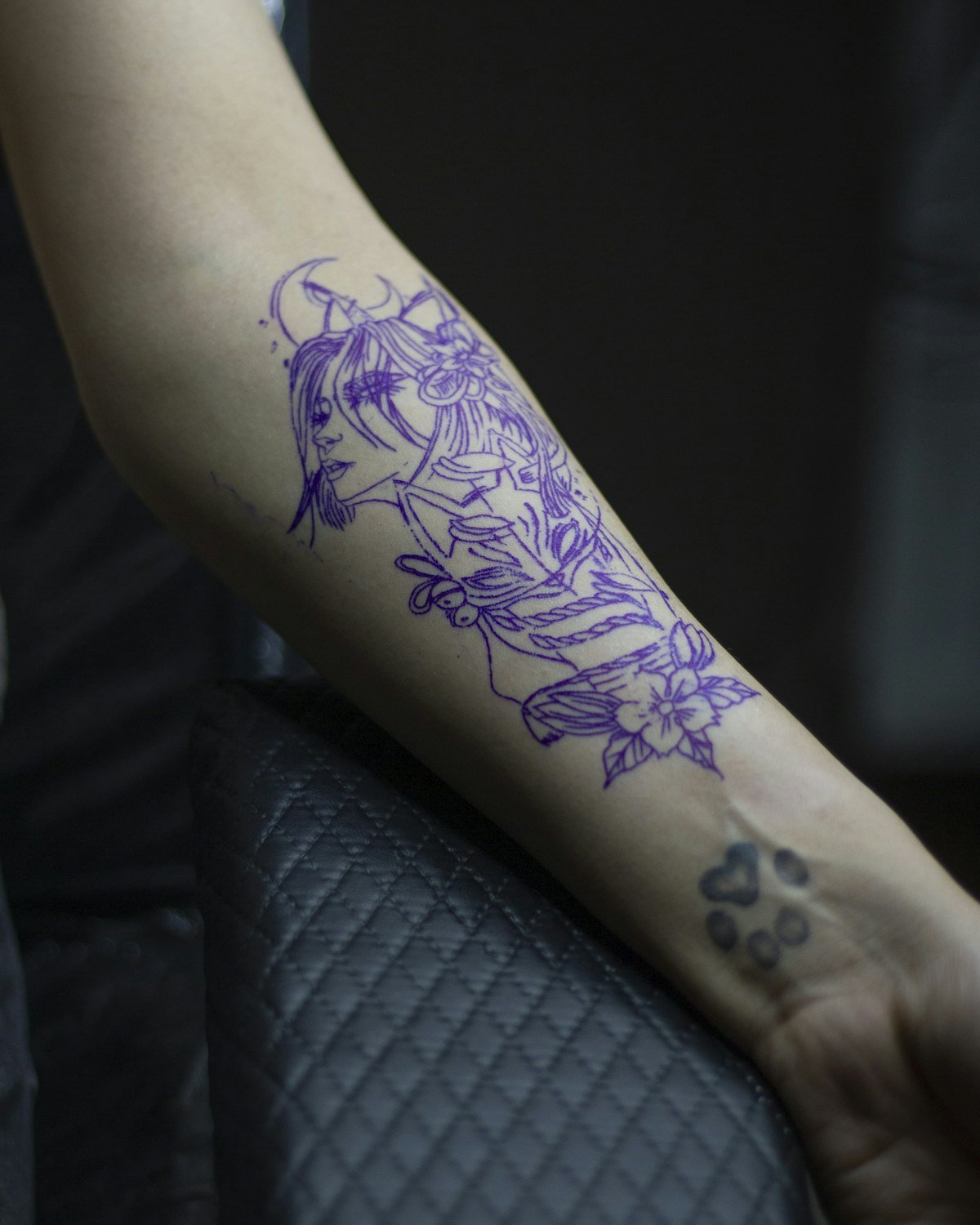 A purple stencil placed on a forearm before tattooing